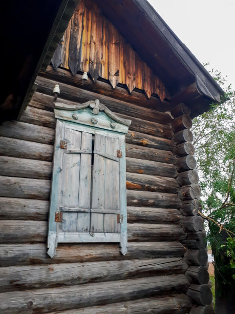 一张废弃的旧木屋的照片，俄罗斯的原木小屋，坚固的建筑，窗花窗板，剥落的蓝色油漆图片下载