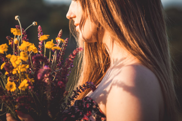 美丽的女孩与野花在草地上，年轻的女人长头发穿着衣服走在自然，夏天温柔的照片在村庄图片下载