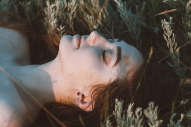 特写美丽的女孩躺在草地上，年轻的女人长头发自然，夏天温柔的照片在村庄图片下载