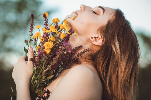 美丽的女孩与野花在草地上，年轻的女人长头发穿着衣服走在自然，夏天温柔的照片在村庄图片下载