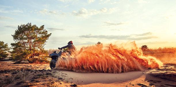 青少年在沙丘上驾驶ATV在沙地上转弯图片下载