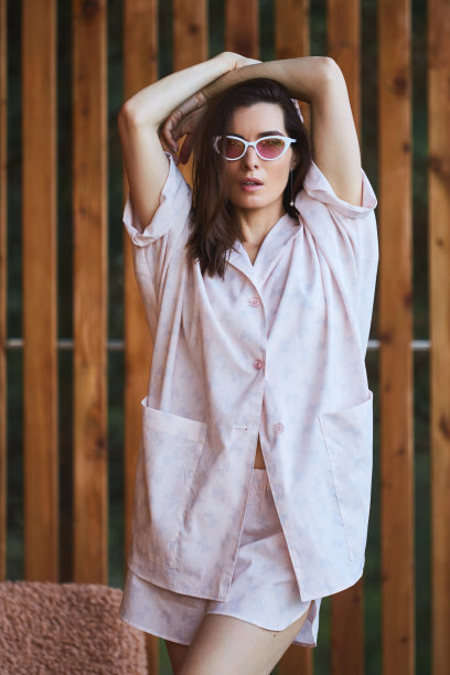 穿着睡衣的女人越过阳台上的木制背景。早上好概念图片下载