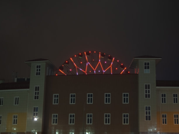一个建筑物的夜景照片，在两座塔之间的中心有一个发光的摩天轮图片下载