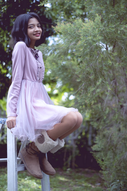 肖像微笑的亚洲年轻女孩与松树在复古的颜色。图片下载