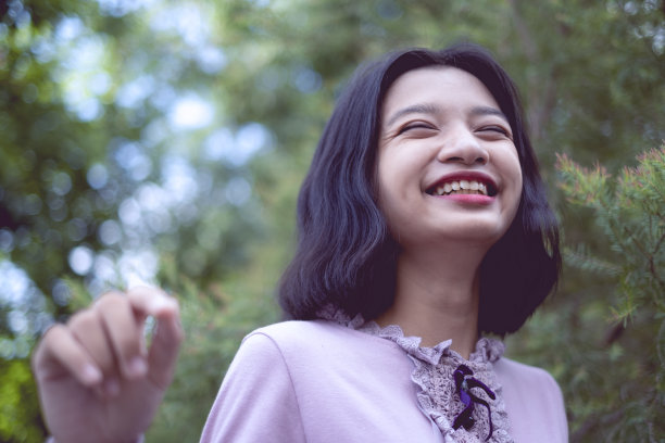 肖像微笑的亚洲年轻女孩与松树在复古的颜色。图片下载