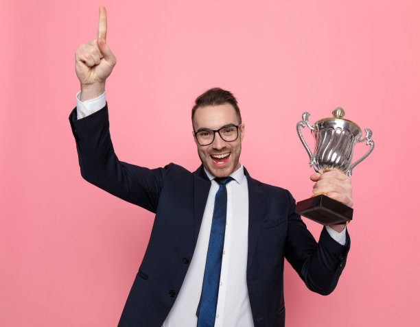 兴奋的年轻商人拿着奖杯，指着别人图片下载