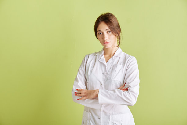 年轻漂亮的女人穿着白色的衣服在绿色的背景下摆姿势。本空间图片下载