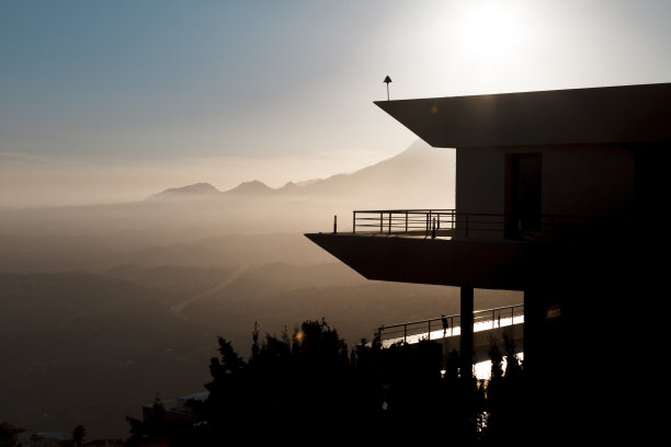 带有阳台的现代建筑的剪影，在美丽的风景背景下，在阳光下的山谷和山脉。图片下载