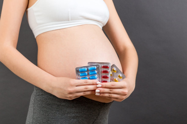 裁剪图像的药物水泡在孕妇的手在彩色背景与复制空间。怀孕期间服用维生素片图片下载
