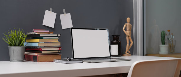 学习桌上有模拟的笔记本电脑，一堆书，记事本和装饰在白色的桌子上图片下载