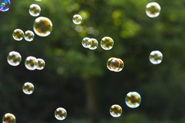 空气中有肥皂泡，绿色的夏日背景。教育、家庭的概念。户外的乐趣。图片下载