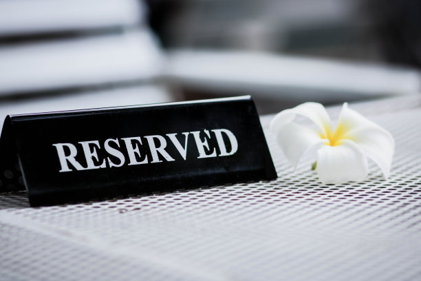 餐厅里预留的黑色金属板。预留金属板在白色的桌子上。复古照片处理。近距离的设置一个预留的标志在餐厅的桌子上。图片下载