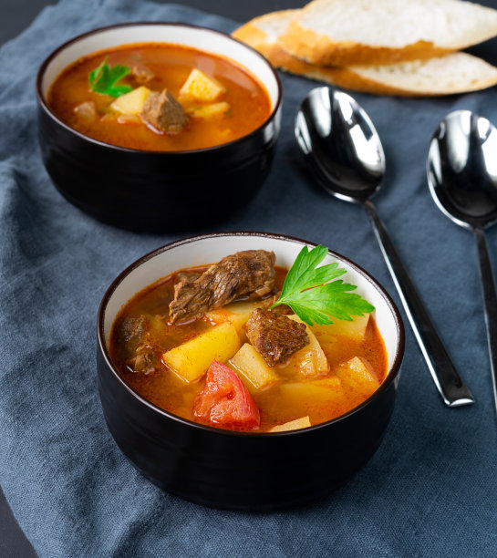 深色盘子里的匈牙利炖牛肉汤，背景是深色。垂直方向图片下载
