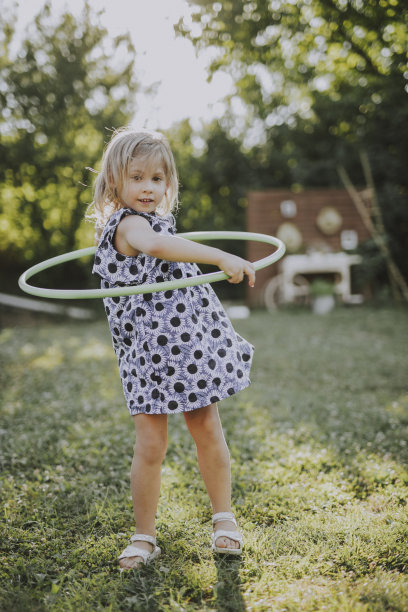 欢快的小女孩穿着裙子在户外玩呼啦圈图片下载