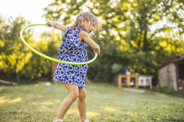 欢快的小女孩穿着裙子在户外玩呼啦圈图片下载