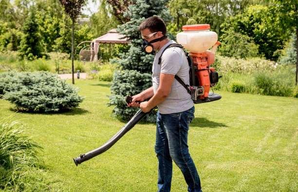 戴着防护面罩和眼镜的园丁向树木喷洒有毒农药图片下载