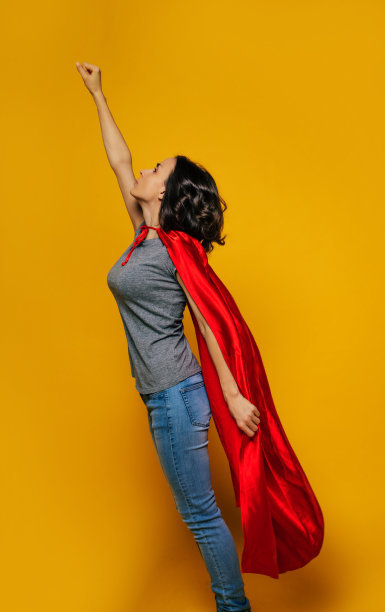 我是一个女超人!一个年轻女孩的全身照片，侧着身子，假装自己是超级英雄，摆着经典的超级英雄姿势，准备飞上天空，开始新的冒险。图片下载