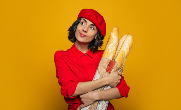 我今天要吃法式面包!一个年轻的法国女人的半长照片，穿着红色贝雷帽，抱着法国面包，计划今晚的晚餐。图片下载