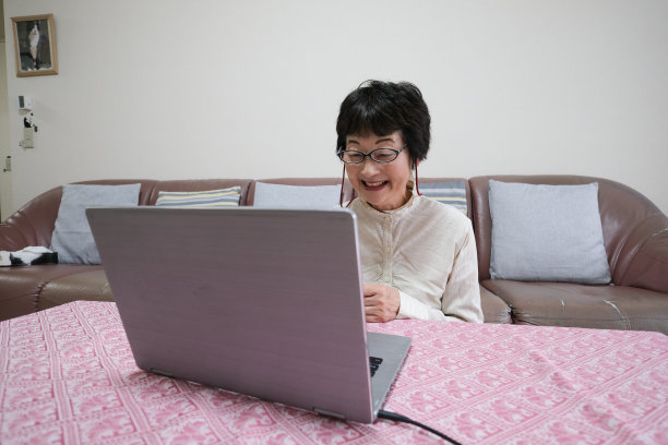 亚洲资深女性微笑着和笔记本聊天图片下载