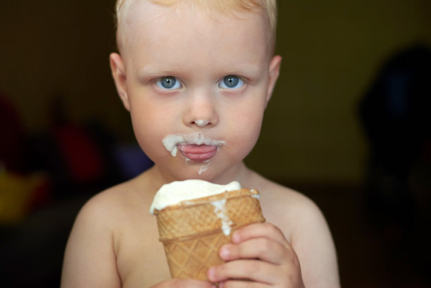 蓝眼睛金发小男孩吃冰淇淋。图片下载