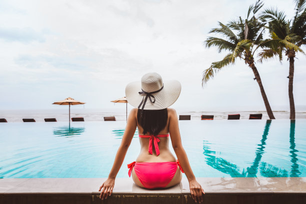 旅行者亚洲女人放松在海滩上的游泳池图片下载
