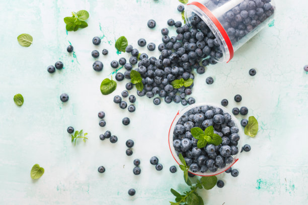 刚洗过的蓝莓，塑料烧杯放在质朴的桌子上图片下载