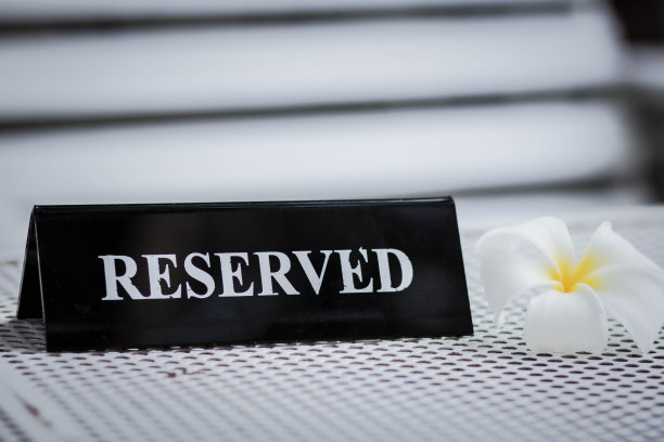 餐厅里预留的黑色金属板。预留金属板在白色的桌子上。复古照片处理。近距离的设置一个预留的标志在餐厅的桌子上。图片下载