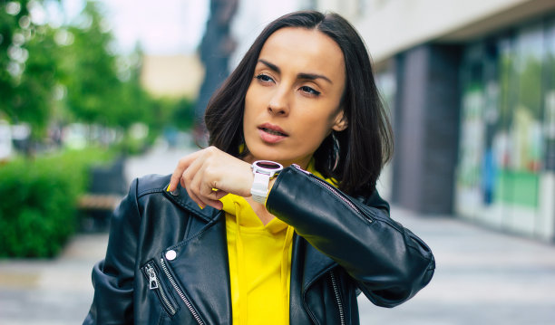 新现代技术!一张年轻女商人在街上的半长照片，拥有智能手表，智能手机，无线耳机。图片下载