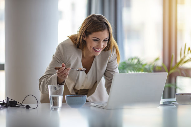 美丽的女商人喜欢在办公室工作时吃玉米片当早餐。图片下载