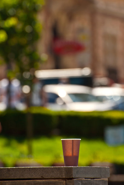 以城市建筑为背景的棕色纸杯。大理石镶边上的咖啡。老城的房屋在背景中显得模糊。清晰度上咖啡。布局设计。图片下载