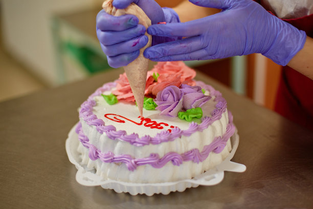 糕点师用糕点袋里的奶油装饰蛋糕图片下载