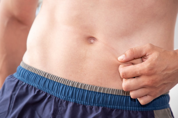 裸男躯干，捏他的皮肤，控制体重或节食的概念图片下载