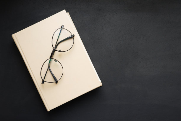 精装黄皮书和阅读眼镜在黑色石板板。图片下载