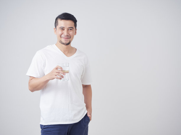 一个年轻人拿着一杯饮用水，背景是白色的图片下载