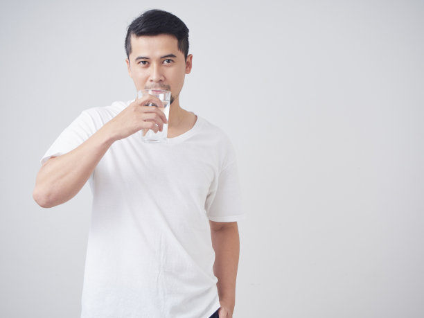 一个年轻人拿着一杯饮用水，背景是白色的图片下载