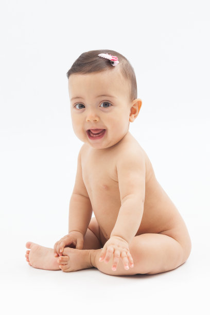 微笑的婴儿坐在白色的背景图片下载