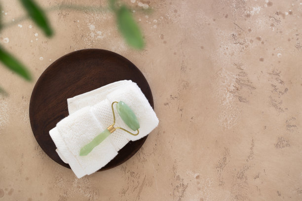 俯视图玉辊和毛巾上的米色背景。简单的家居美容护肤和家居护理理念。本空间图片下载