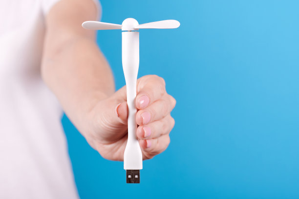 手持白色USB风扇。孤立在蓝色背景。图片下载