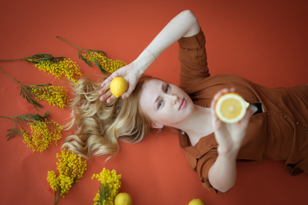 黑白照片与一个快乐的年轻金发女子在橙色的背景和柠檬在她的橙色衬衫图片下载