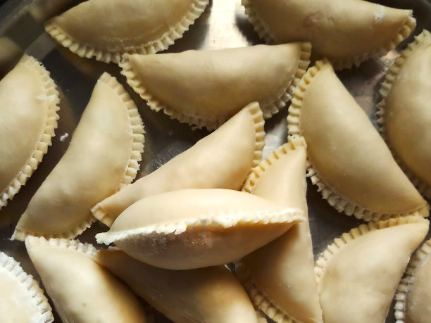 这是自制gujiya的特写照片，传统的印度甜饺子，里面包着干果，放在不锈钢盘子里(塔利)，准备用来油炸，胡里节的甜点，从高处俯瞰图片下载