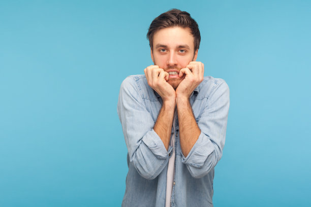 焦虑症,抑郁症。一幅紧张不安、忧心忡忡的男人的肖像，穿着工人牛仔衬衫，咬着指甲图片下载