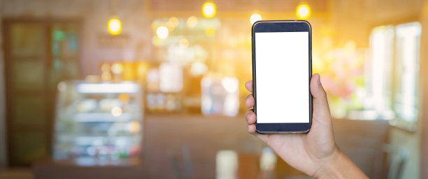 男人手持手机智能手机，平板电脑，手机通过模糊或散焦图像的咖啡店或自助餐厅，客户在餐厅模糊背景与散焦，复古的颜色，食物在线电话购物图片下载