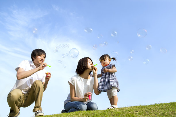 父母和小女儿在蓝天下玩肥皂泡图片下载