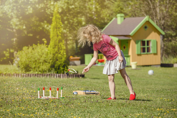 可爱的6岁小女孩在阳光明媚的夏日在自家花园里玩抛绳游戏。休闲活动的概念。图片下载