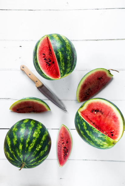 新鲜成熟的西瓜在白色的木质表面图片下载