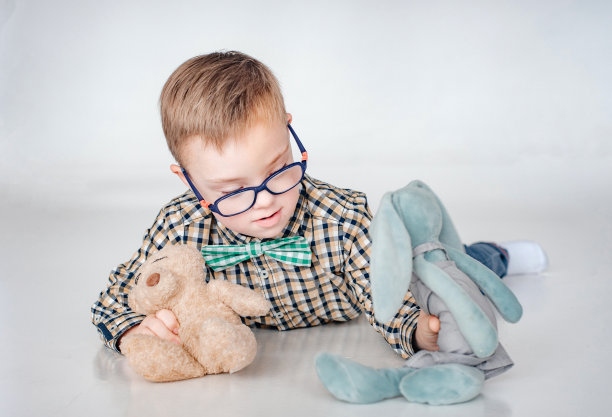 一个小男孩躺在地板上玩玩具。图片下载