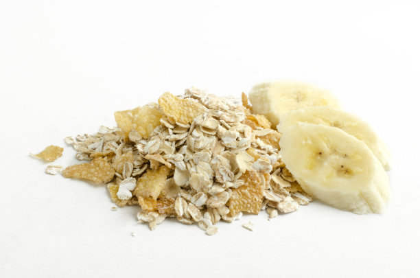 在白色的背景上的一堆桨粉，玉米片和美味的香蕉片的特写。美味早餐的一部分图片下载