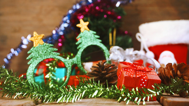 红色礼盒和松果与绿色闪烁花哨的眼镜装饰圣诞派对主题。图片下载