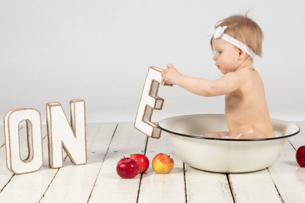 一个漂亮的一岁小女孩在盆里洗澡。在你的第一个生日拍摄照片。图片下载