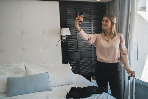女商人在酒店房间用手机自拍。图片下载